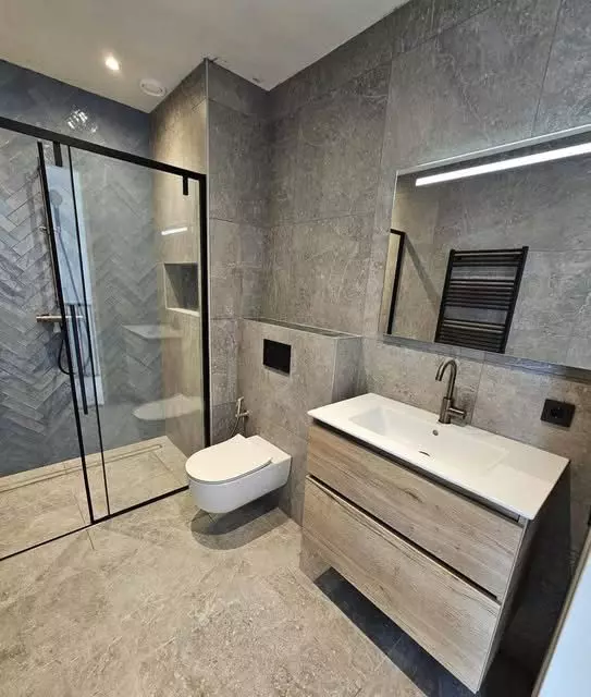 Luxe badkamer renovatie in Deventer met grijze marmerlook tegels en gunmetal kranen
